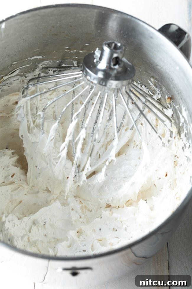 Divine Cloud Candy Delights 5 Whipped meringue for the divinity recipe in a stand mixer with the whip attachment.