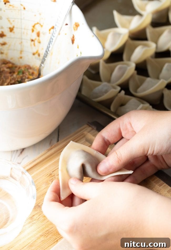 Ultimate Wor Wonton Soup 8 Step-by-step image illustrating the folding technique for perfect wontons.