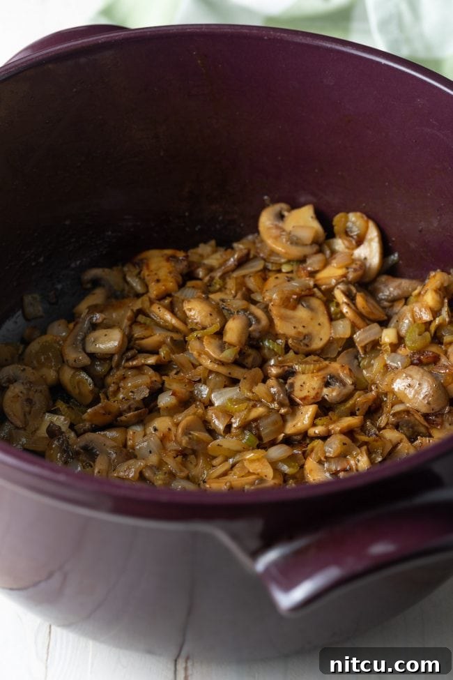 Classic Hungarian Mushroom Soup Made Vegan and Gluten Free 5 Sliced mushrooms and chopped onions sautéing in a large soup pot.