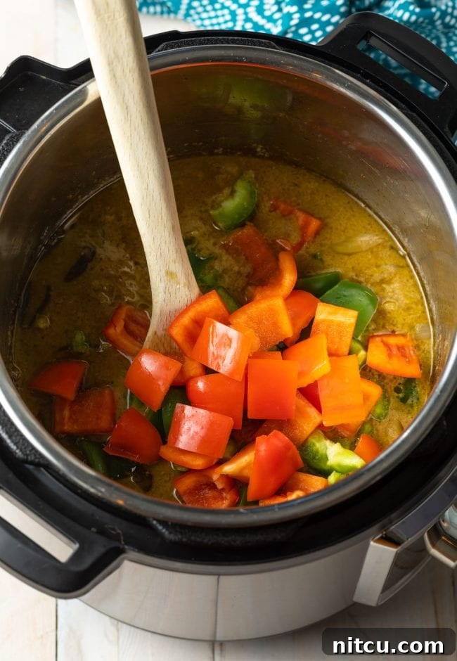Effortless Instant Pot Thai Green Curry 8 Red and green bell peppers being added to the simmering green curry in the Instant Pot.