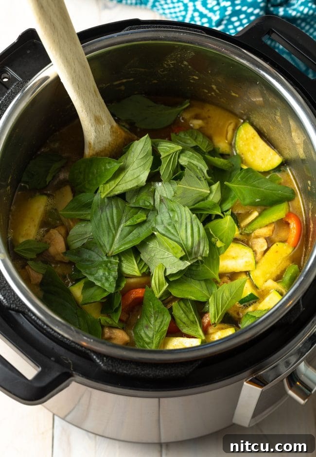 Effortless Instant Pot Thai Green Curry 9 Fresh Thai basil leaves being stirred into the finished Instant Pot Green Curry.