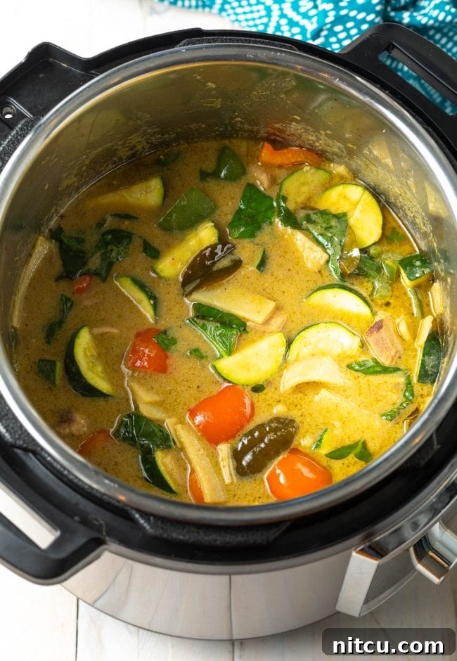 Effortless Instant Pot Thai Green Curry 10 A vibrant green chicken curry bubbling gently in the Instant Pot, nearly ready to serve.