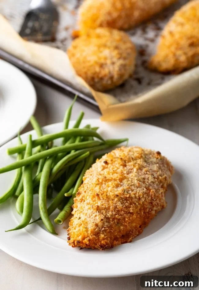 Crispy baked buffalo chicken breast served on a plate with fresh green beans, ready to enjoy.