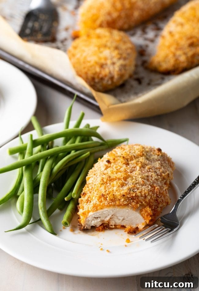 Easy oven-baked buffalo chicken breast, sliced to show the tender cooked chicken, served with a side of green beans.