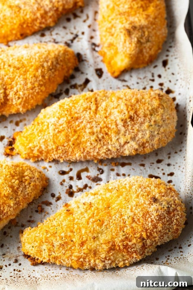 Glorious oven-baked buffalo chicken breast with a reddish-orange hue after baking, resting on a plate.