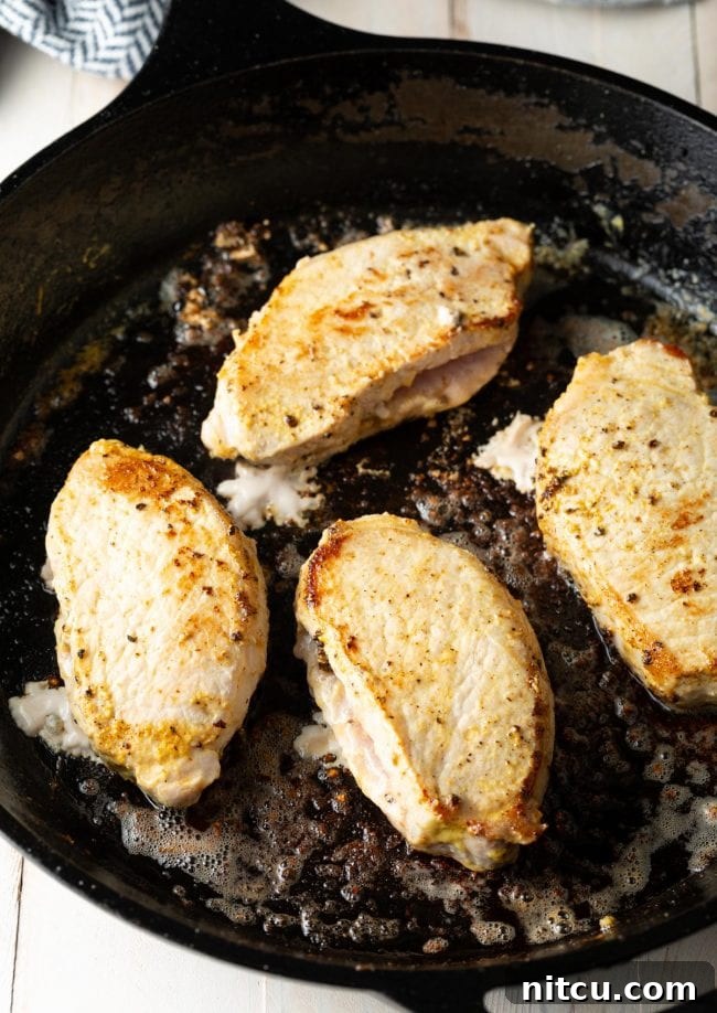 Tender Apple-Stuffed Baked Pork Chops 6 top view of pan seared pork chops in a cast iron skillet golden