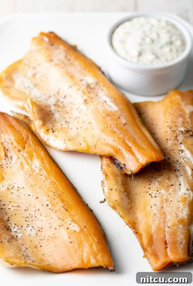 A platter featuring several beautifully smoked trout fillets, ready for serving.
