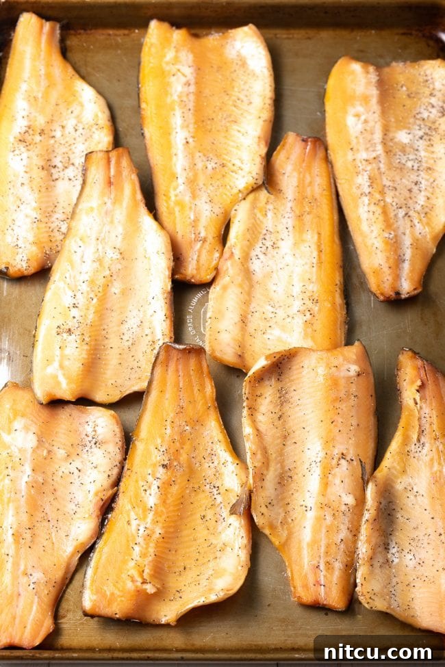 Perfectly smoked trout fillets lined up on a baking sheet, showcasing their golden hue.