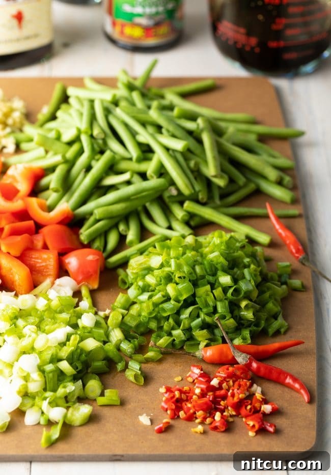 Freshly chopped green beans, red bell pepper, scallions, and Thai bird chiles, prepped for stir-frying.