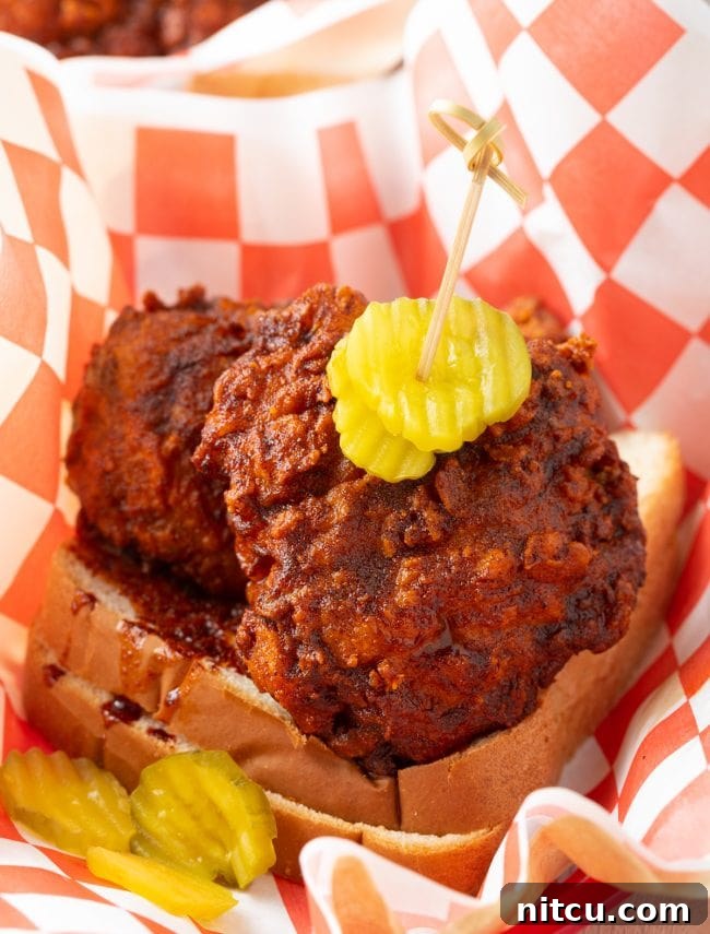 Nashville Hot Chicken 2 A close-up of golden-brown Nashville hot chicken pieces glistening with spicy oil, served in a rustic metal basket, promising a crispy and flavorful experience.