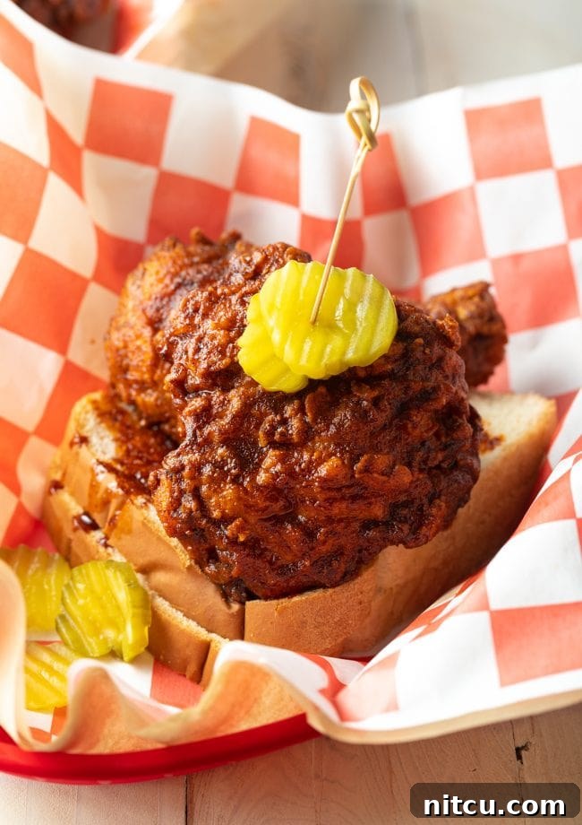 Nashville Hot Chicken 13 A basket of Nashville hot chicken, perfectly spiced and golden, served on white bread with dill pickles on top.