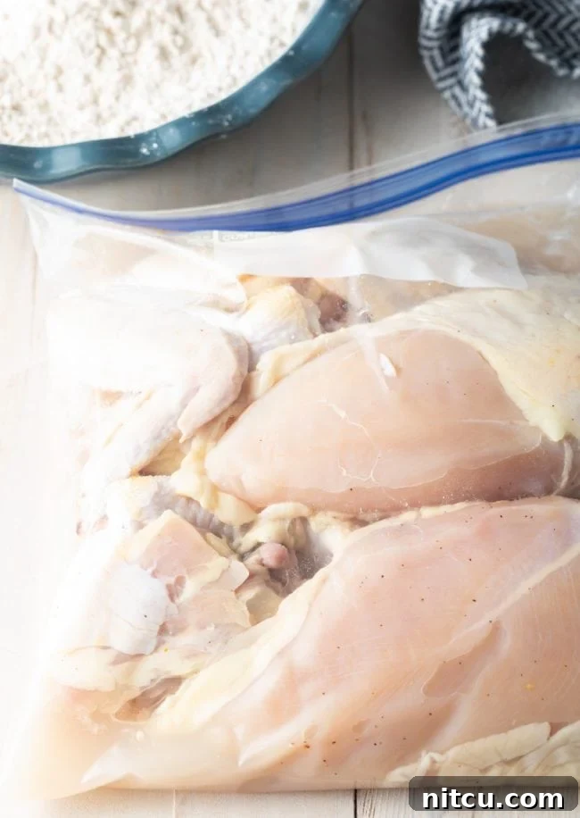 Nashville Hot Chicken 5 Chicken pieces marinating in a clear zip-top bag with a pickle juice brine, ready for flavoring.