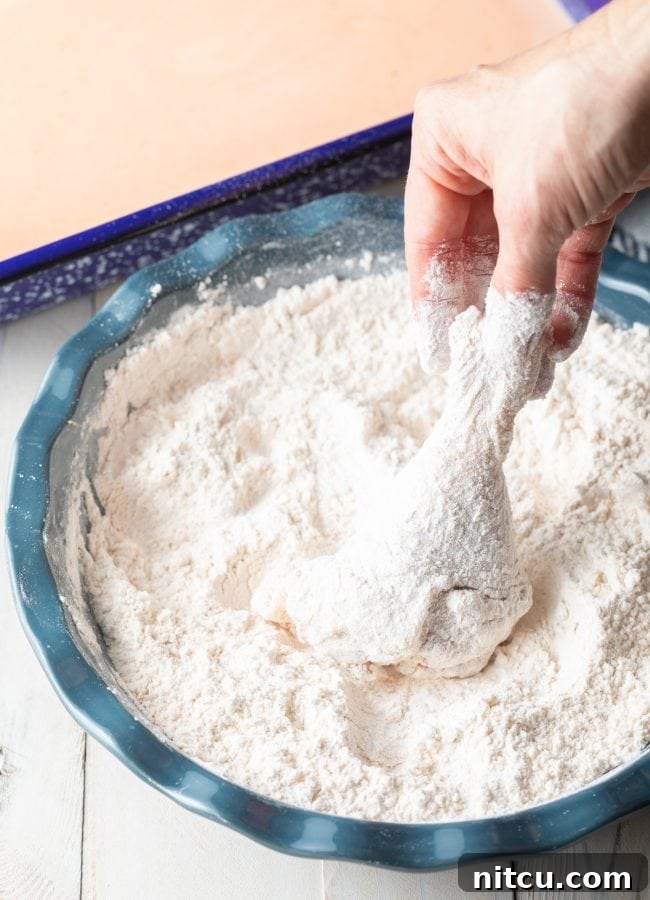 Nashville Hot Chicken 6 Raw chicken pieces being thoroughly coated in a dry flour mixture, ensuring a perfect crispy crust.