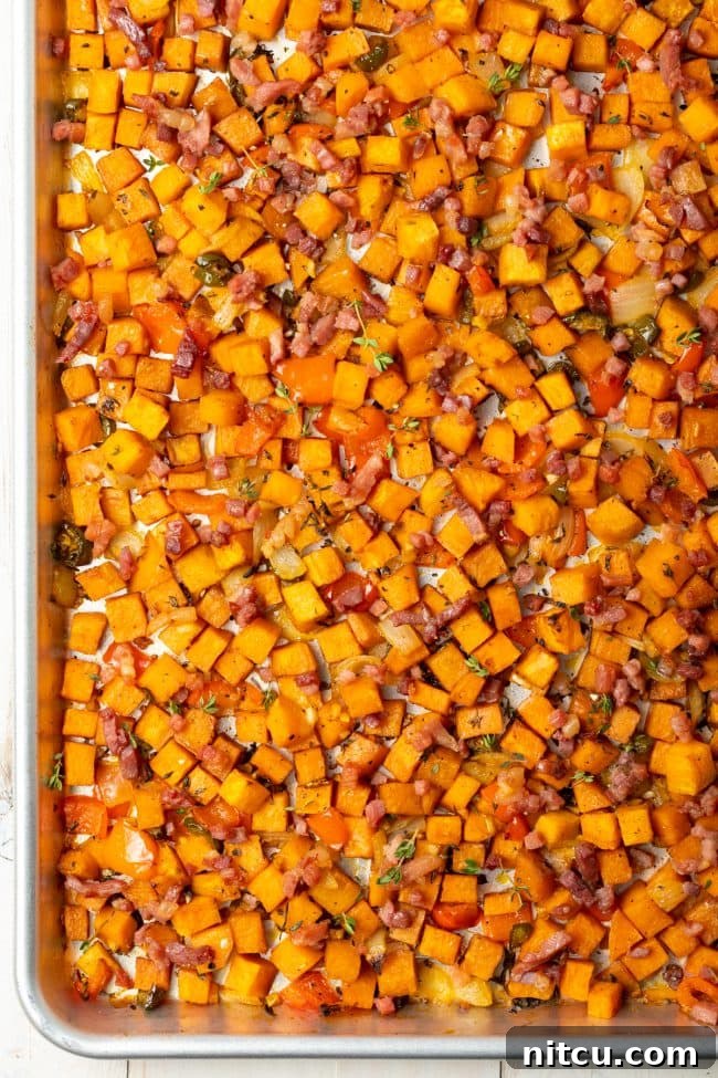 Sweet Potato and Bell Pepper Hash 6 An overhead shot showcasing perfectly cooked sweet potato hash browns spread across a baking sheet, featuring crispy edges and vibrant colors.