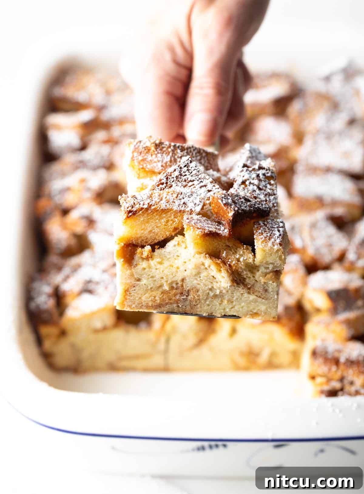 Hand with square of casserole to camera.