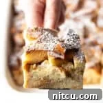 A slice of French toast casserole overnight recipe being held up with a spatula over a white baking dish.