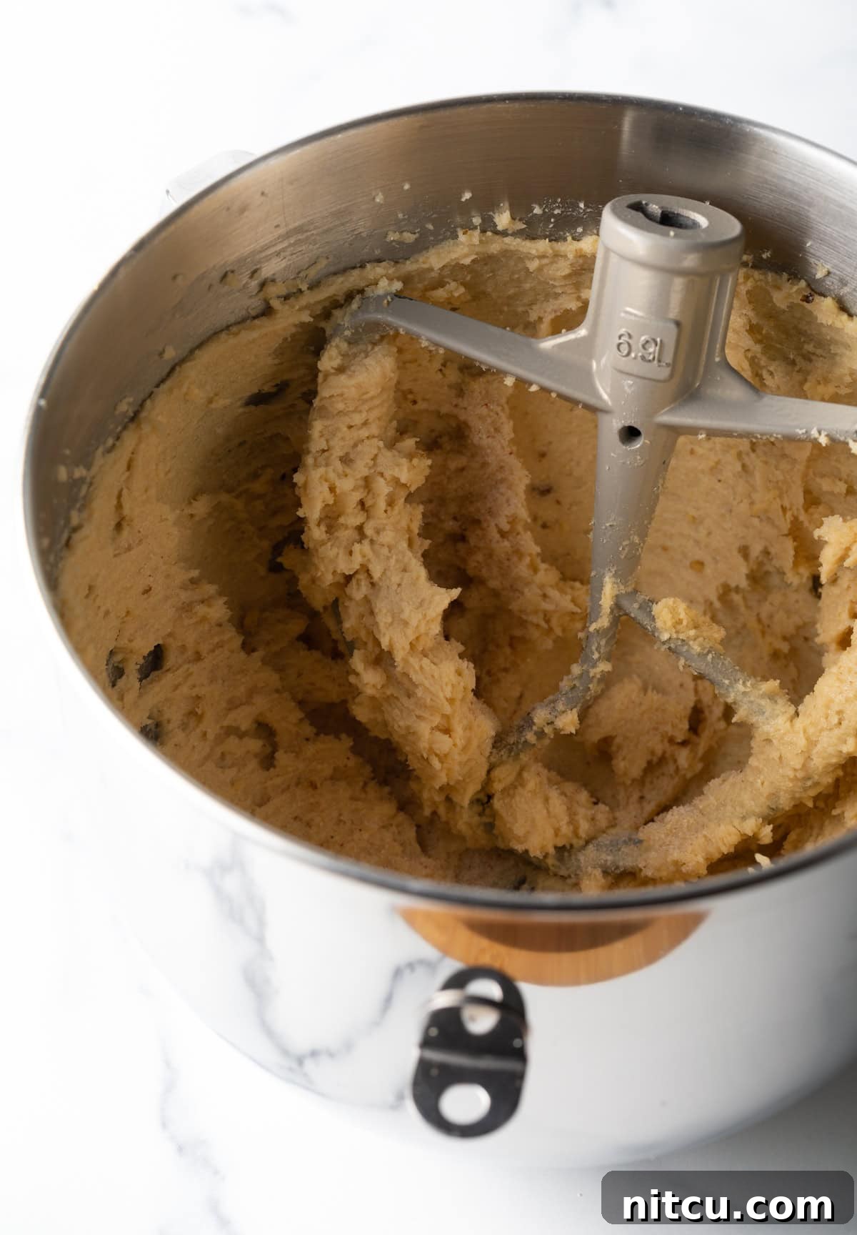 A stand mixer is mixing a butter and sugar mixture for walnut chocolate chip cookies.
