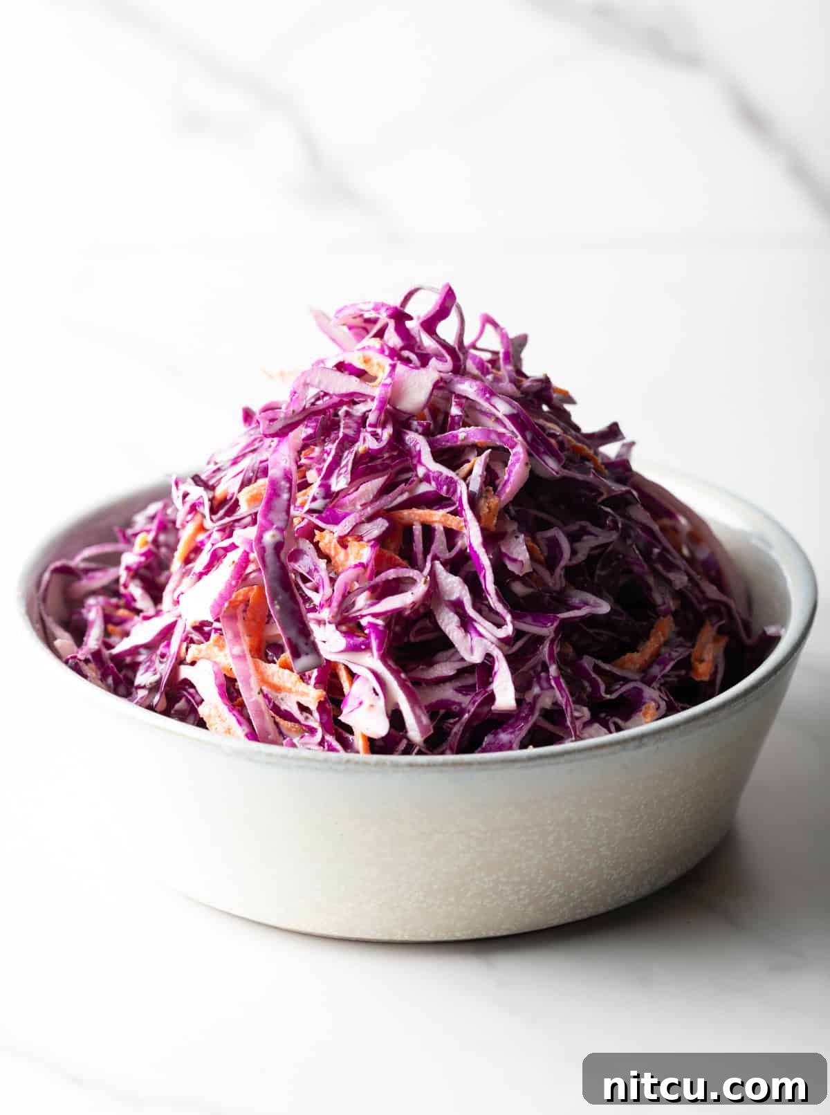 Crimson Cabbage Crunch 5 A white bowl filled with a red cabbage slaw recipe.