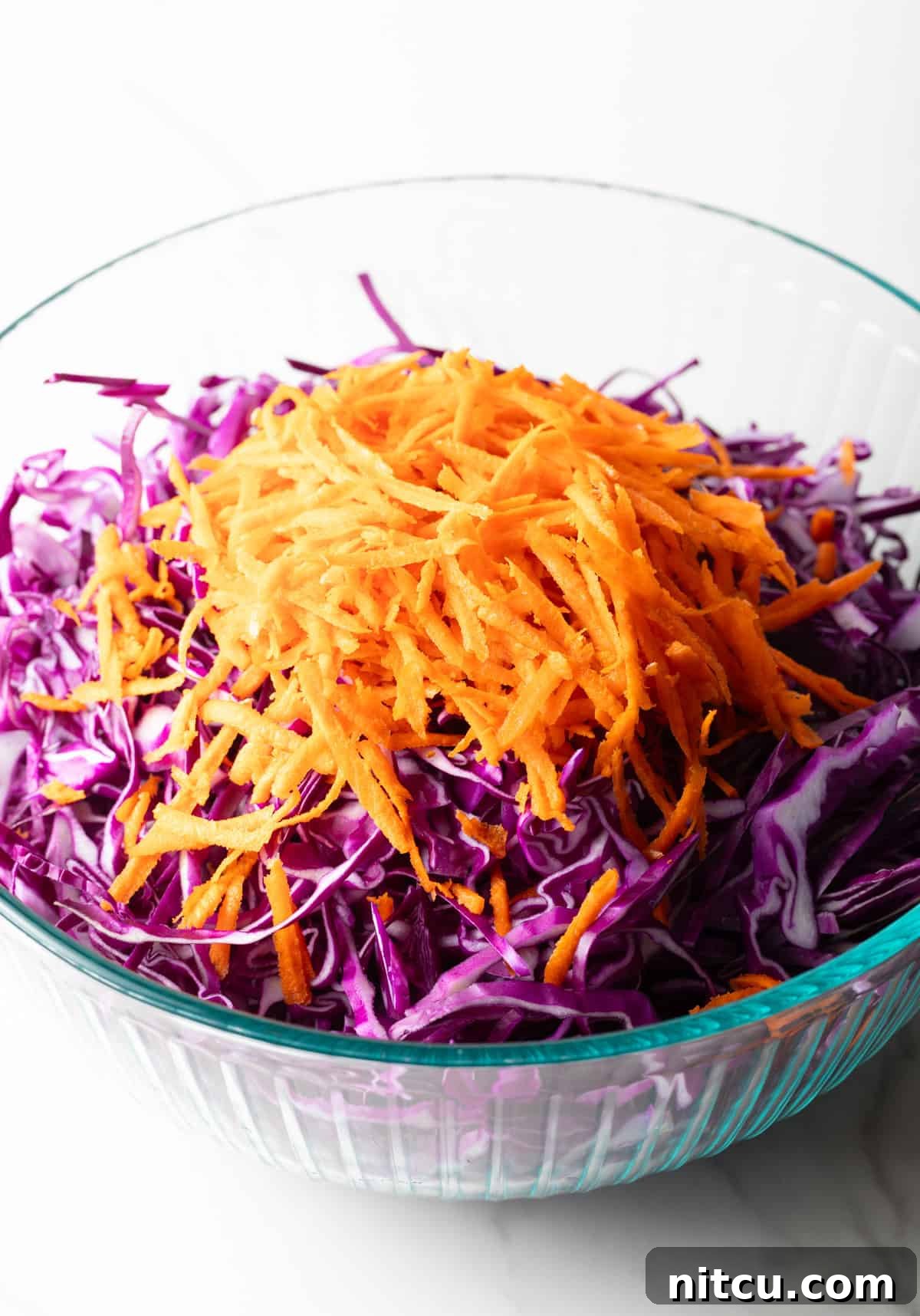 Crimson Cabbage Crunch 6 Shredded red cabbage, red onion, and carrots in a glass bowl.
