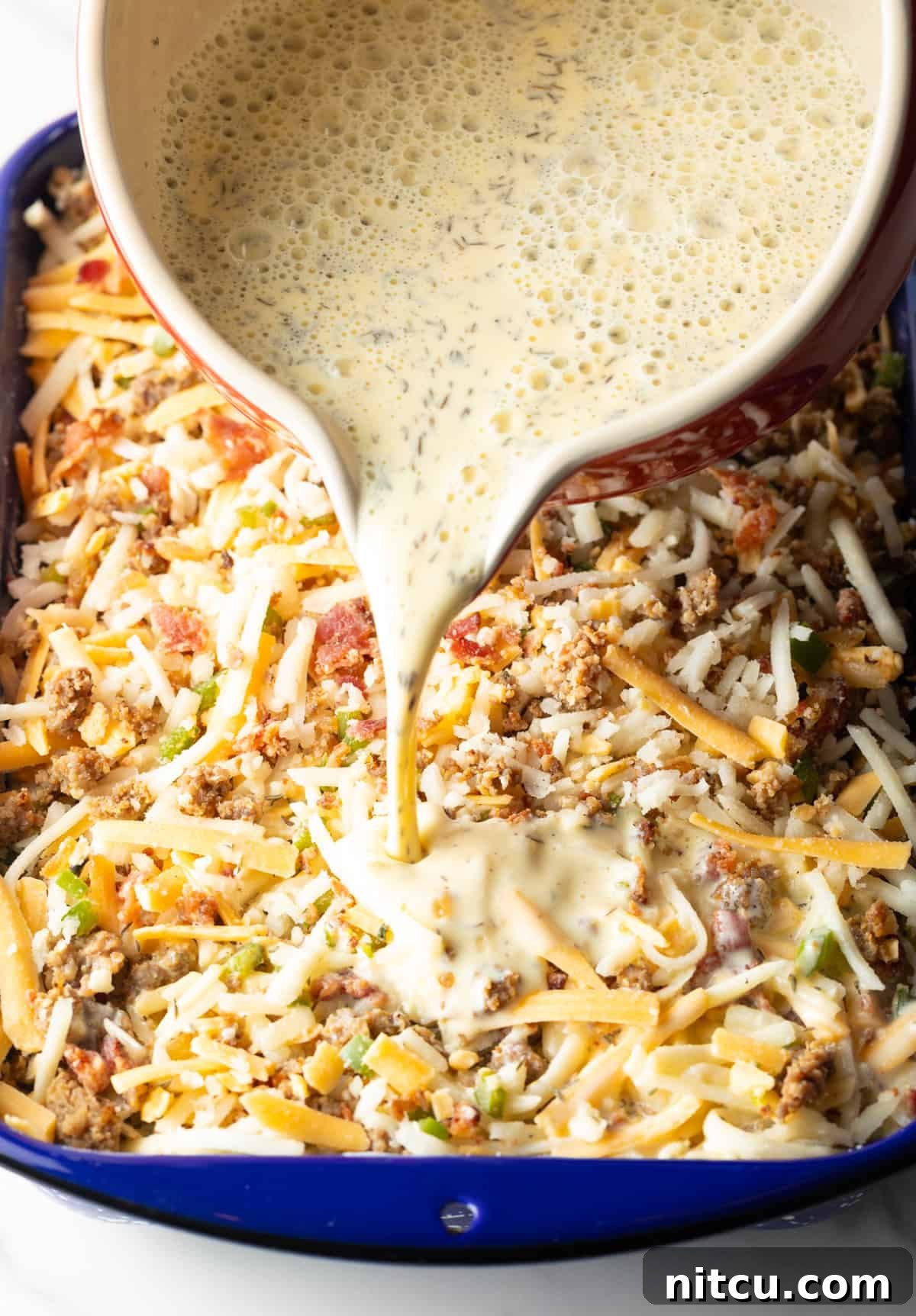 Golden Hash Brown Breakfast Bake 10 A smooth egg and cream mixture is gracefully poured over the assembled ingredients for a hash brown breakfast casserole, ensuring every component is saturated.