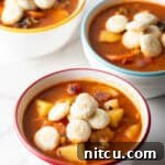 Three white bowls filled with a Manhattan clam chowder recipe topped with oyster crackers.