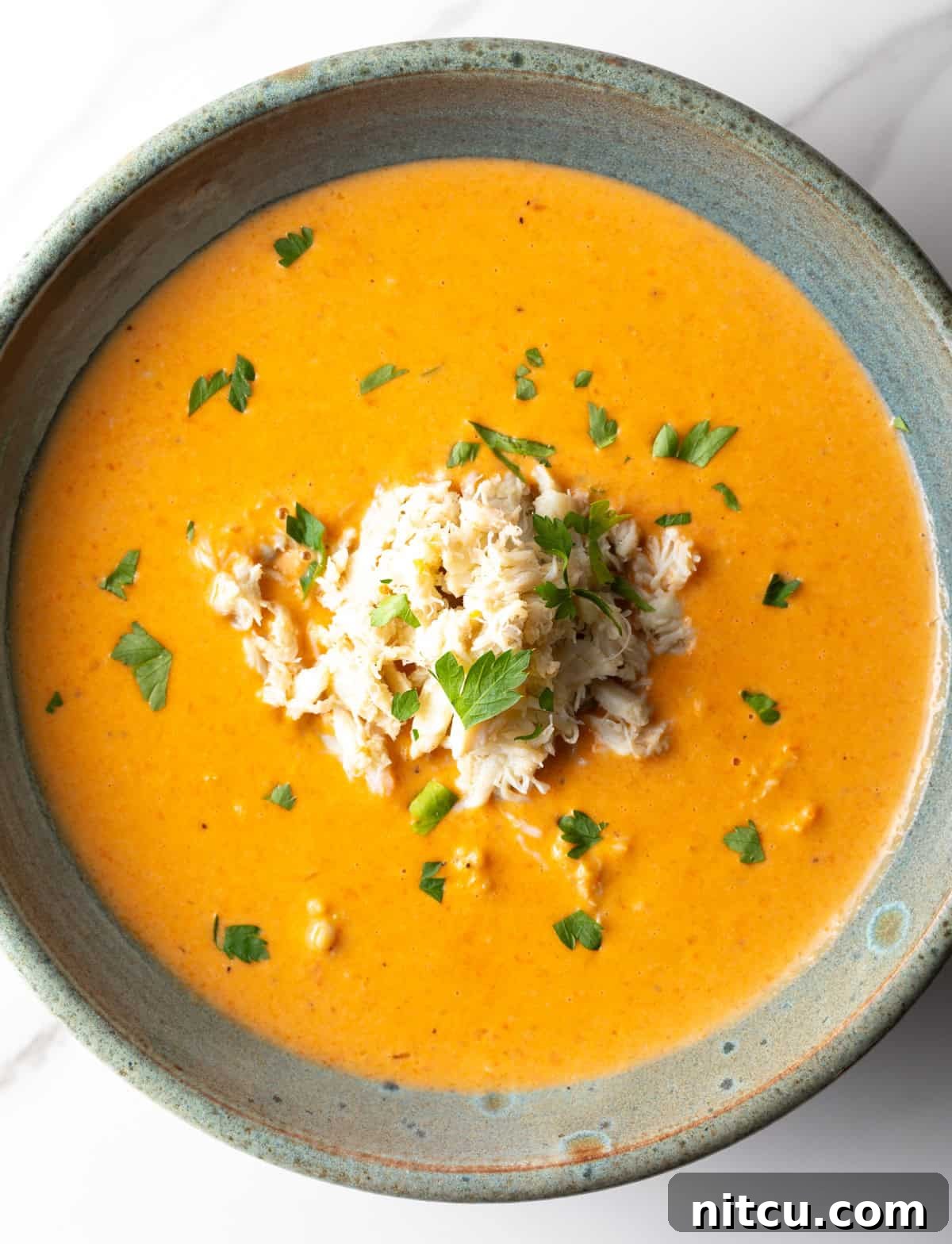Decadent Crab Bisque 12 An overhead shot of a crab bisque recipe in a grey bowl.