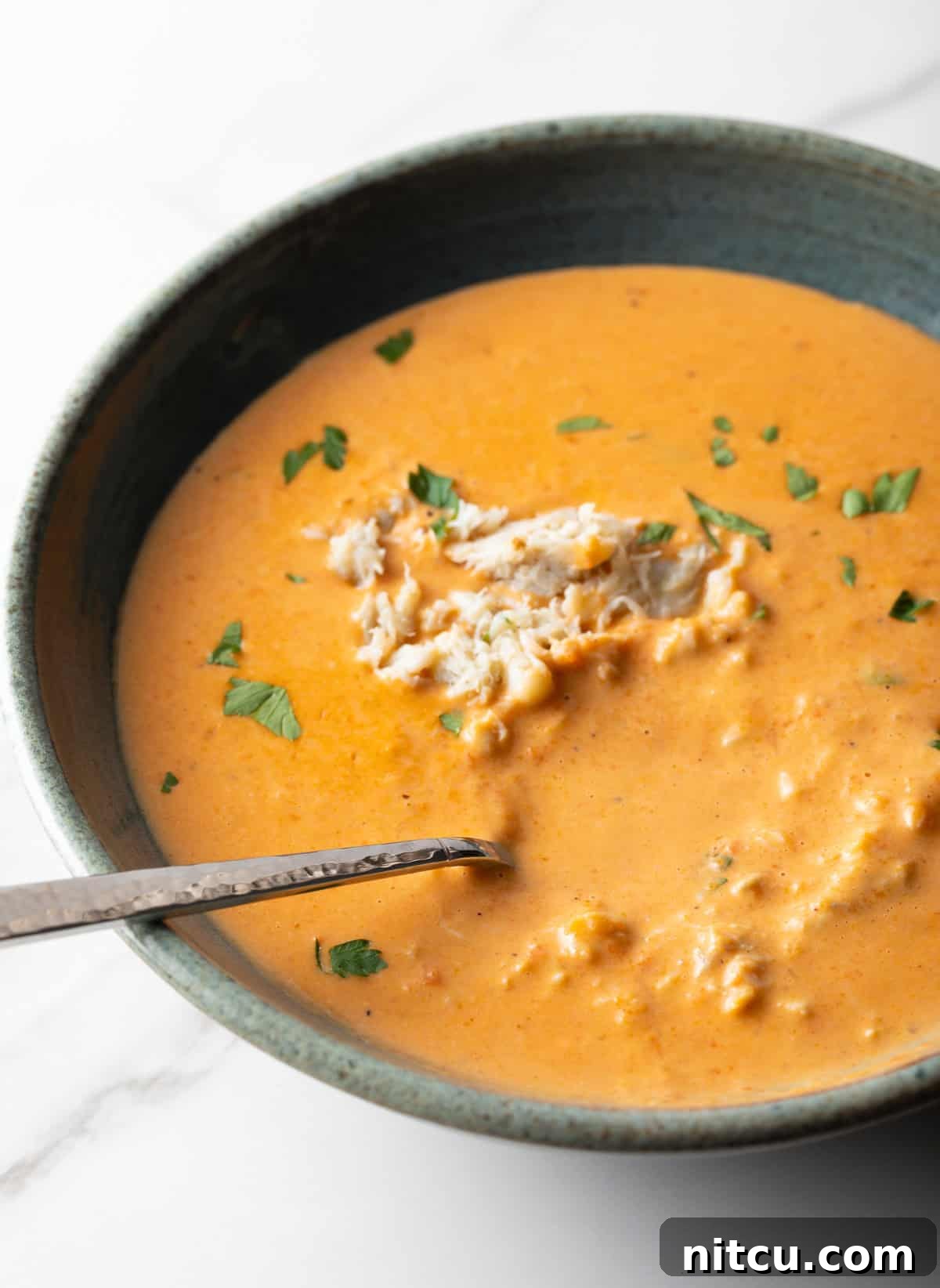 Decadent Crab Bisque 13 A bowl of easy crab bisque soup with a metal spoon in the bowl.