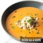 Decadent Crab Bisque 14 A black bowl filled with creamy crab bisque soup with crab meat and parsley on top.