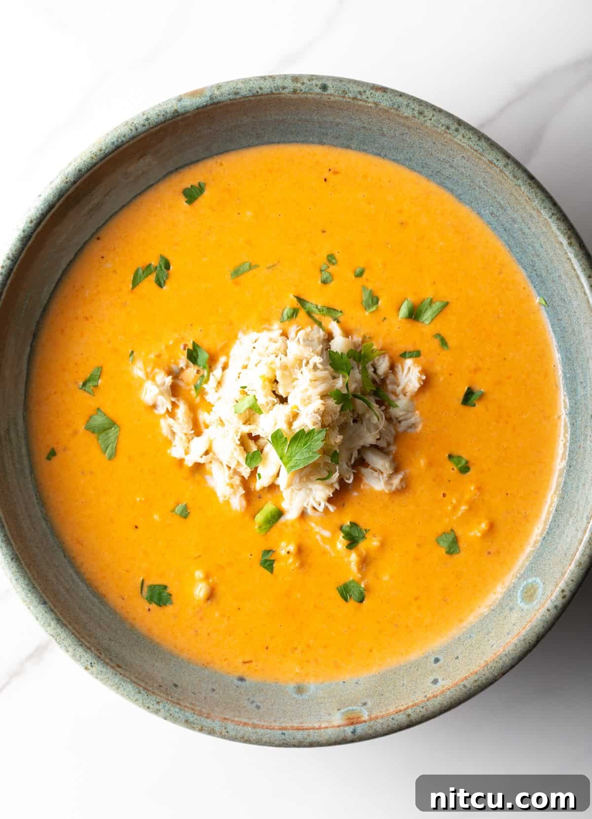 Decadent Crab Bisque 3 An overhead shot of a crab bisque recipe in a black bowl.