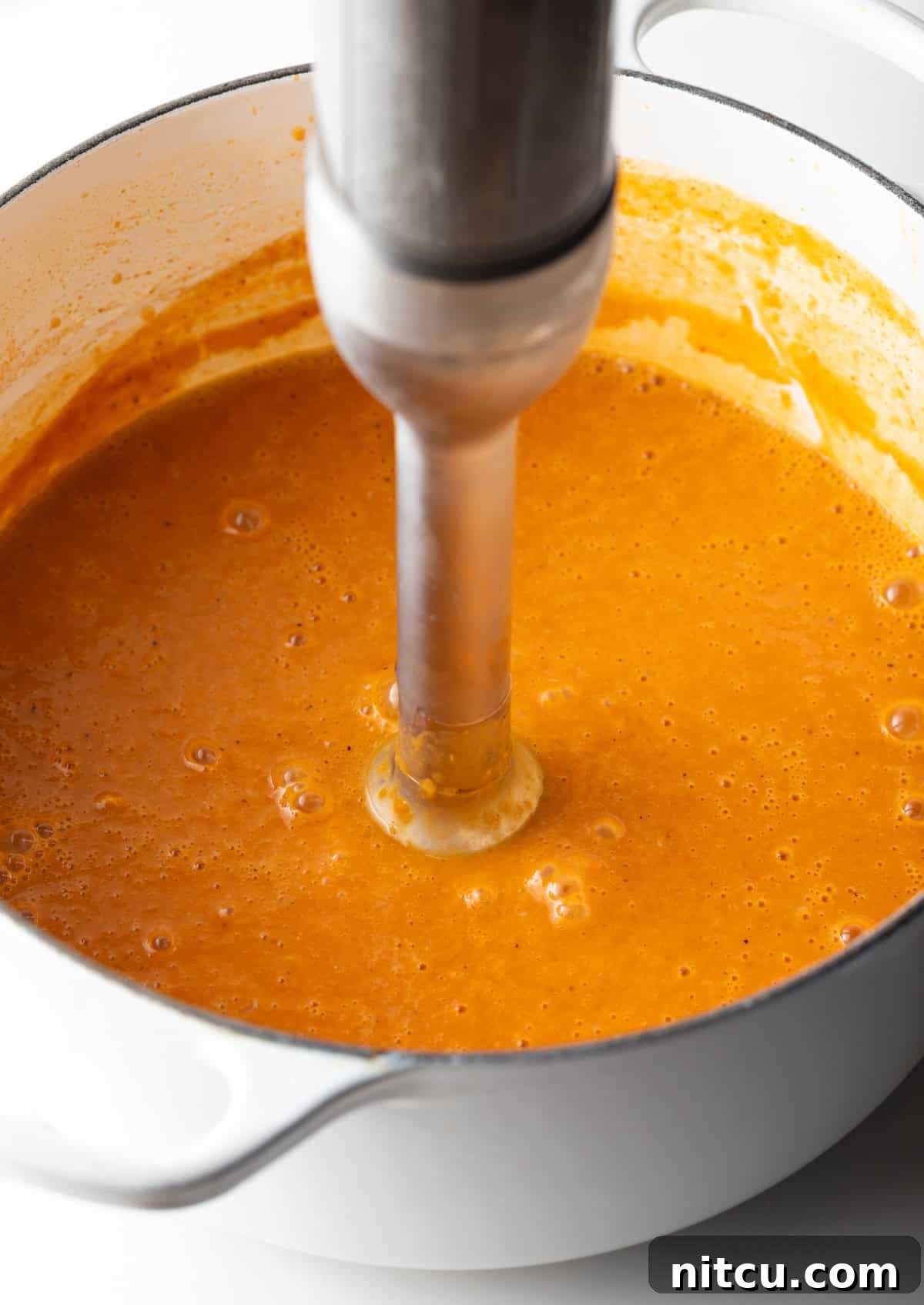 Decadent Crab Bisque 8 An immersion blender is blending a crab bisque soup base.