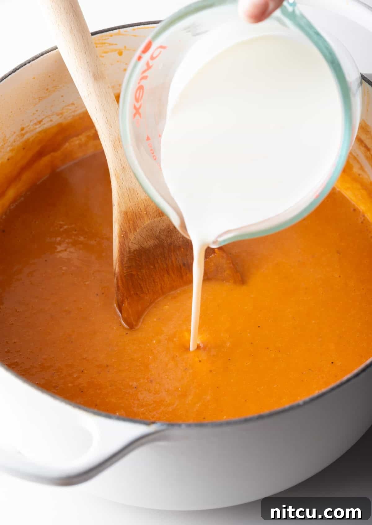 Decadent Crab Bisque 9 Heavy cream is being added to a crab bisque recipe soup base.