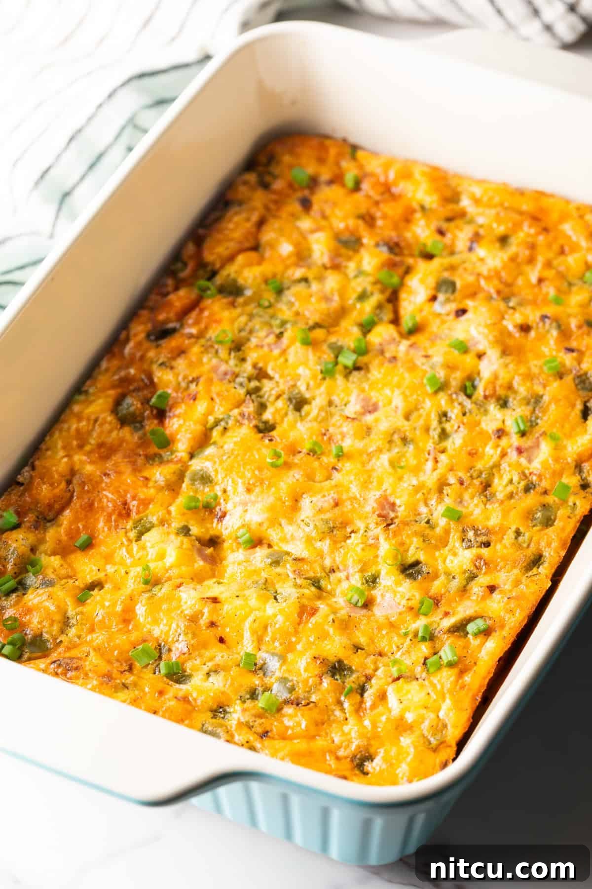 Mile-High Breakfast Casserole 12 A freshly baked Denver omelette casserole in a white baking dish.