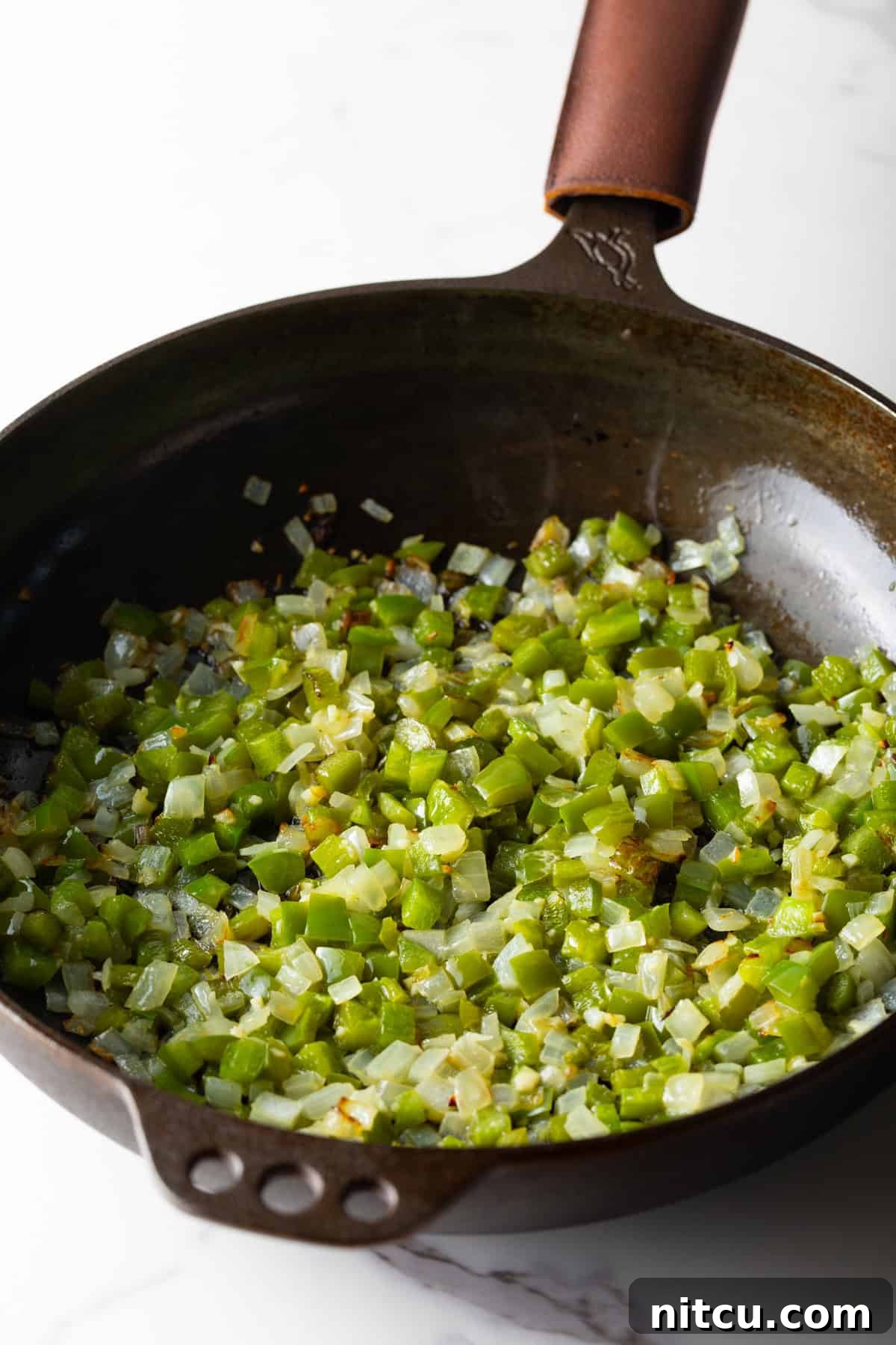 Mile-High Breakfast Casserole 7 Diced vegetables for a baked omelet casserole are being sautéed in a black skillet.